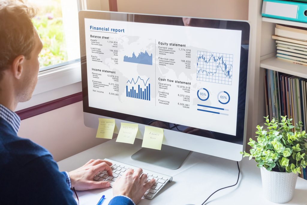 Businessman working on Financial Report of corporate operations on computer screen with Balance Sheet, Income Statement, and key performance indicators on custom software