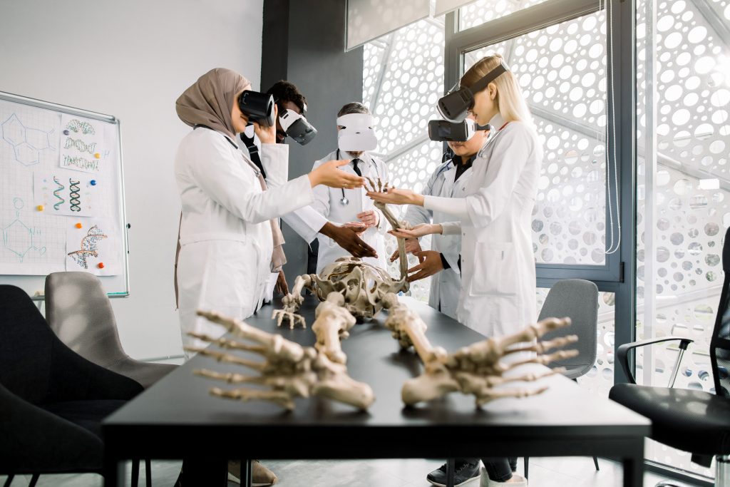 Male professor teacher using Virtual Reality Glasses to teach skeleton anatomy for multiethnic students in class. Education, VR, Tutoring, New Technologies and Teaching Methods concept, virtual reality for training