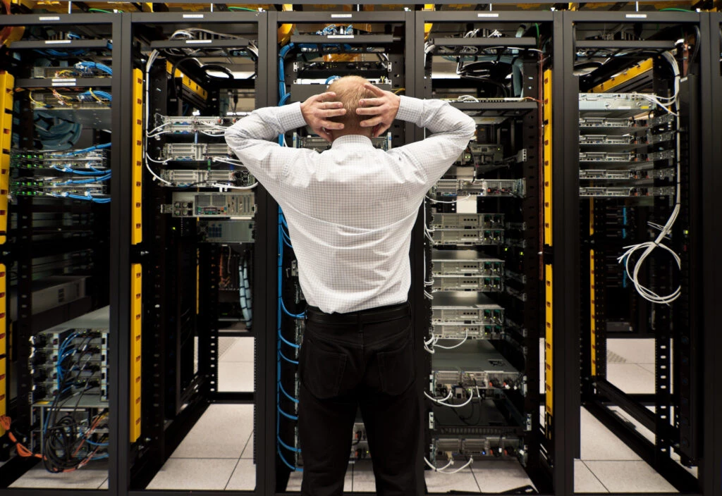 Man looking astonished in a network data center. legacy software, outdated it systems