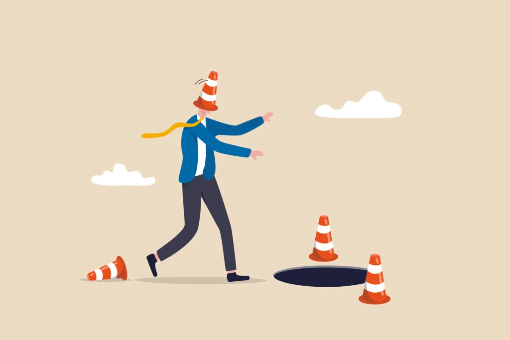 Blind and frustrated business direction, mistake or failure, trap or crisis ahead, risk and uncertainty concept, blindfold businessman cover with pylon walking to fall into the hole or business trap.